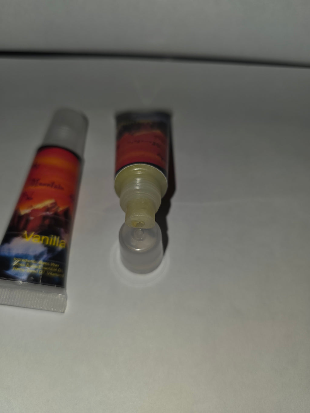 Vanilla lip balm squeeze tubes showing capped tube and open applicator
