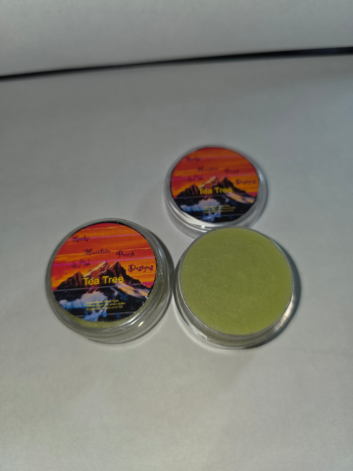 Tea Tree Lip Balm canisters with an open canister showing the balm