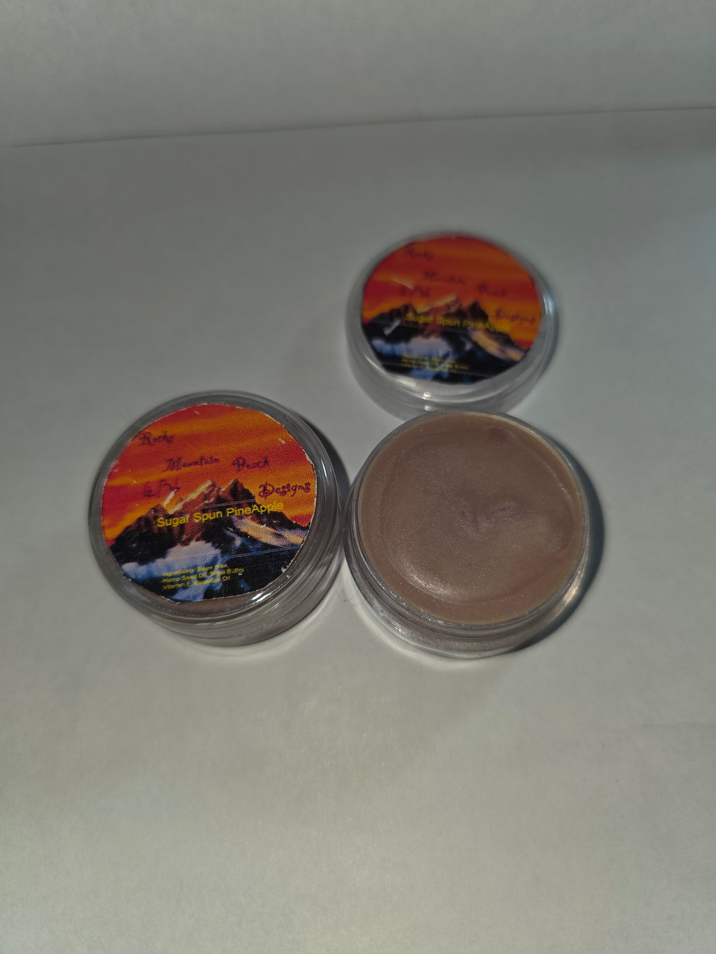 Sugar Spun Pineapple Lip Balm canisters with an open canister showing the balm